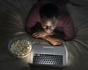 Homem assistindo no notebook aos melhores documentários da Netflix.